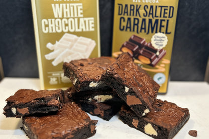 Brownies with Whittaker's chocolate bars on a white surface against a dark background