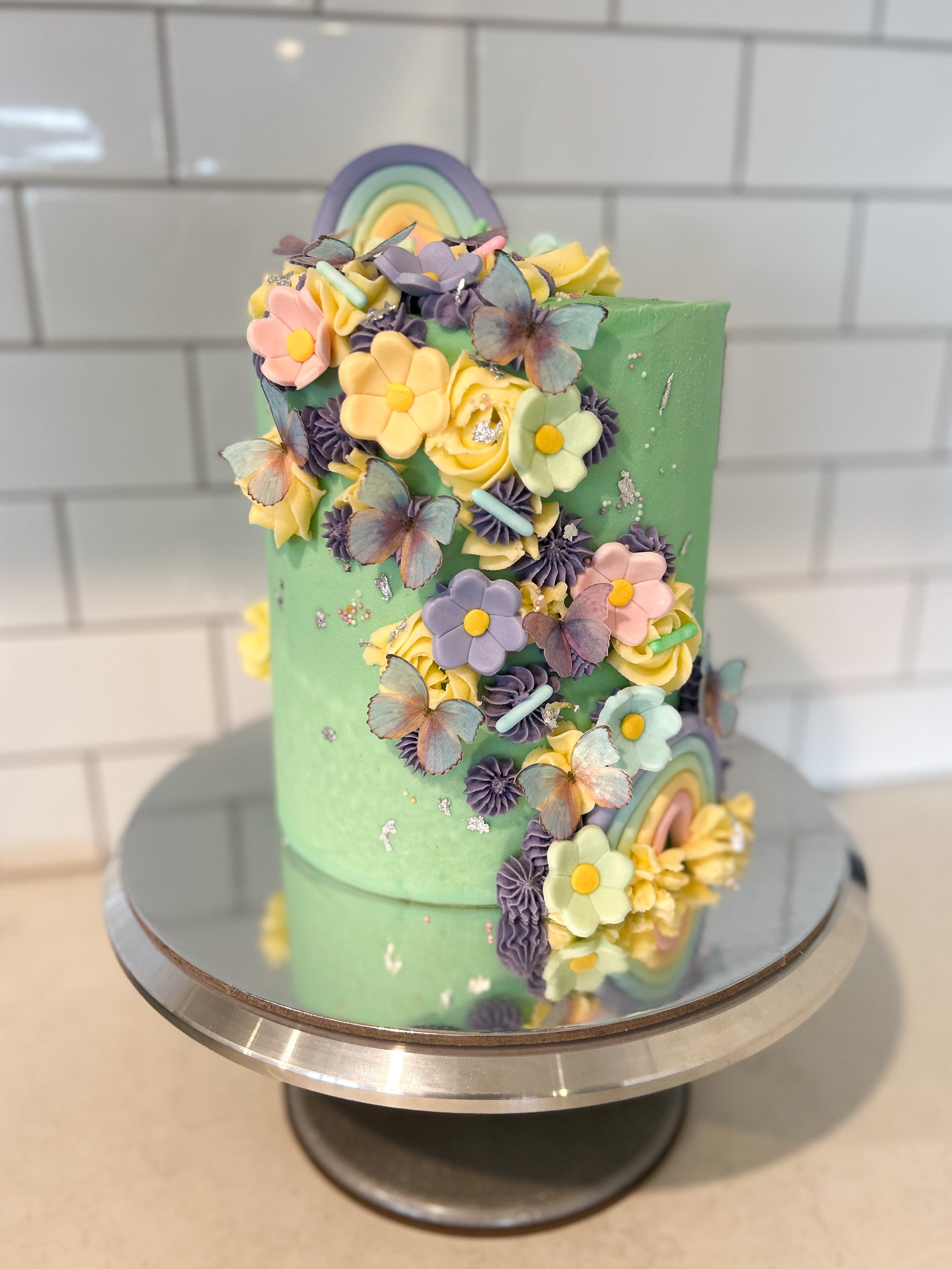 Tall 6 inch cake in pastel tones with rainbows and butterflies on it 